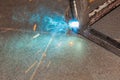 An experienced man performs work with a welding machine by fastening metal parts in an industrial