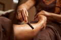 Experienced masseuse using wooden tool during traditional Thai foot massage
