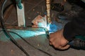 An experienced person performs work with a welding machine, fixing metal parts, removing blue smoke and yellow sparks and