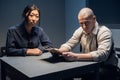 An experienced police officer and his young assistant sit at the table and sort out the case