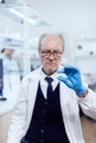 Experienced scientist in busy laboratory holding glass slide