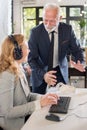 Experienced senior businessman explaining something to female co-worker at her workplace in office. Royalty Free Stock Photo