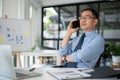 Experienced senior businessman having a serious phone call with his employee while sitting in the office room Royalty Free Stock Photo