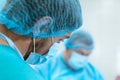 An experienced surgeon in a mask and gown operates in a sterile operating room with an assistant and an anesthesiologist..A group