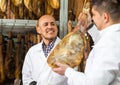 Experienced technologist with butcher checking drying wurst and jamon