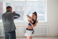 An experienced trainer puts the technique of blows to a young girl in the boxing hall Royalty Free Stock Photo