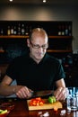 waiter cutting fruit for a mixed drink on the counter. Preparation of cocktail for customers.