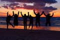 Experiencing the vitality of nature. Silhouette of a group of people jumping on the beach at sunset. Royalty Free Stock Photo