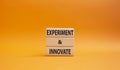 Experiment and innovate symbol. Concept words Experiment and innovate on wooden blocks. Beautiful orange background. Business and Royalty Free Stock Photo