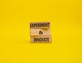 Experiment and innovate symbol. Concept words Experiment and innovate on wooden blocks. Beautiful yellow background. Business and Royalty Free Stock Photo