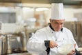 Male chef wearing toque whisking mixture with metal whisk in bowl in restaurant kitchen, copy space Royalty Free Stock Photo