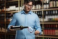 Expert Asian Sommelier Pouring Red Wine in Glass Amidst an Extensive Wine Cellar Collection