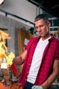 Expert carpenter burning a wood leg with a professional gas burner. Flames and smoke, fire and timber. Portrait of Royalty Free Stock Photo