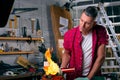 Expert carpenter burning a wood leg with a professional gas burner. Flames and smoke, fire and timber. Portrait of