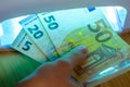Expert checks paper euro banknotes with infrared or ultraviolet light detector