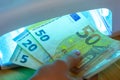 Expert checks paper euro banknotes with infrared or ultraviolet light detector