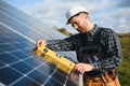 Expert is inspecting quality of a solar batterys. Worker in uniform and helmet with equipment. Ecology power