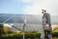 Expert is inspecting quality of a solar batterys. Worker in uniform and helmet with equipment. Ecology power