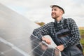 Expert is inspecting quality of a solar batterys. Worker in uniform and helmet with equipment. Ecology power