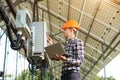 Expert is inspecting quality of solar panels. Man in hardhat standing with laptop near electrical equipment Royalty Free Stock Photo