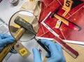 Expert police examines with magnifying glass a hammer in laboratory forensic equipment