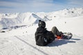 Back view of snowboarder sitting on the snow and admiring the winter landscape. Royalty Free Stock Photo