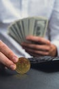 Expert trader hands showing Bitcoin coin digital gold after counting income banknotes of dollar cash on calculator