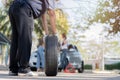 Expertise mechanic man in uniform holding a tire for help a woman for changing car wheel on the highway, car service, repair, Royalty Free Stock Photo