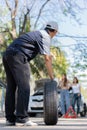 Expertise mechanic man in uniform holding a tire for help a woman for changing car wheel on the highway, car service, repair, Royalty Free Stock Photo