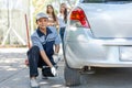 Expertise mechanic man  in uniform using force trying to unscrew the wheel bolts nuts and help a woman for changing car wheel on Royalty Free Stock Photo