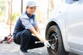 Expertise mechanic man  in uniform using force trying to unscrew the wheel bolts nuts and help a woman for changing car wheel on Royalty Free Stock Photo