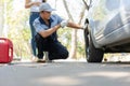 Expertise mechanic man  in uniform using force trying to unscrew the wheel bolts nuts and help a woman for changing car wheel on Royalty Free Stock Photo