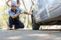 Expertise mechanic man  in uniform using force trying to unscrew the wheel bolts nuts and help a woman for changing car wheel on Royalty Free Stock Photo