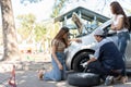 Expertise mechanic man  in uniform using force trying to unscrew the wheel bolts nuts and help a woman for changing car wheel on Royalty Free Stock Photo