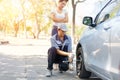 Expertise mechanic man  in uniform using force trying to unscrew the wheel bolts nuts and help a woman for changing car wheel on Royalty Free Stock Photo