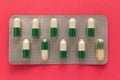 Expired white and green capsules in medicine box. Pills over red Royalty Free Stock Photo