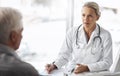 Explain your symptoms to me. a mature female doctor working with a senior male patient in her office in the hospital. Royalty Free Stock Photo