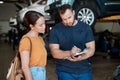 Explaining the vehicle diagnosis to his customer. a woman talking to a mechanic in an auto repair shop. Royalty Free Stock Photo