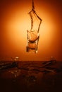 Exploding Glass cup with water shattering over orange background.