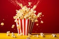 Exploding Popcorn In Classic Striped Box Against Red Backdrop. Generative AI