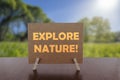 Explore nature text on card on the table with sunny green park background Royalty Free Stock Photo