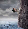 Explorer climbs a mountain with the risk to fall on the sea with sharks Royalty Free Stock Photo