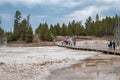 Explorers hiking on wooden pathway amidst geyser basin at national park