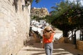 Exploring Alicante in Spain. Young traveler woman walking in the neighborhood Santa Cruz looking at Mount Benacantil with Santa