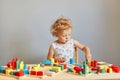 Exploring educational activities. Playful games in daycare. Kindergarten room of wonder. Focused wavy haired blonde infant baby