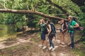 Exploring, researches and expedition concept. Four tourists are hiking near the river in a wild spring wood, guy is looking in the Royalty Free Stock Photo