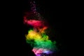 Explosion of colorful Holi powder on black background. Vibrant color dust particles textured background Royalty Free Stock Photo