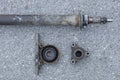 Exposed central bearing and shell from a propeller shaft. Removed from a car and lying on the ground. Rusty bearing outer face and