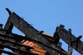 Black charred burnt wooden roof rafters after fire under blue sky Royalty Free Stock Photo