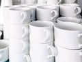 Exposed on stacks of white clean ceramic cups and saucers. Dishes in the restaurant for tea and coffee Royalty Free Stock Photo